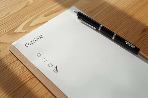 Checklist clipboard with a pen on a wooden desk